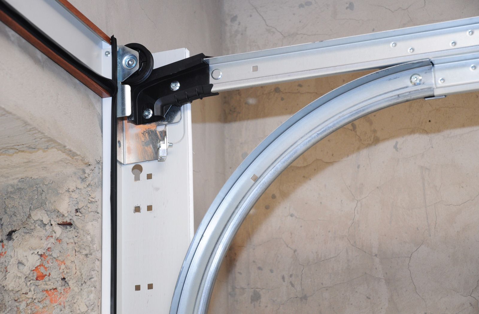 Garage door opener rail and motor mounted beside a partially open door