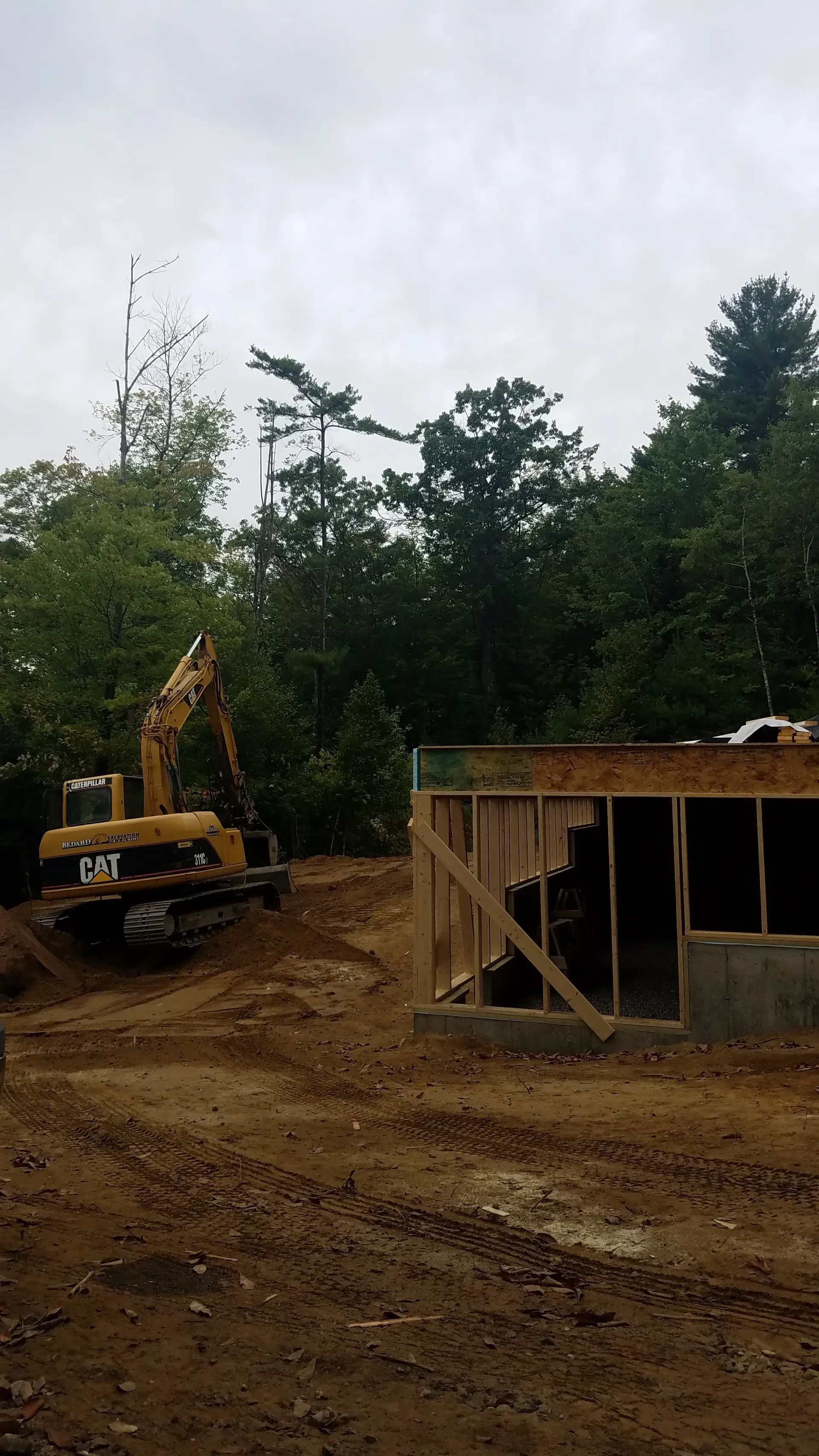 A construction site with a yellow excavator in the middle of it.