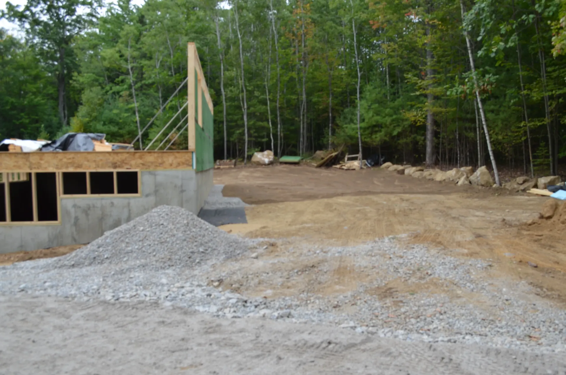 A pile of gravel is sitting in front of a house under construction.