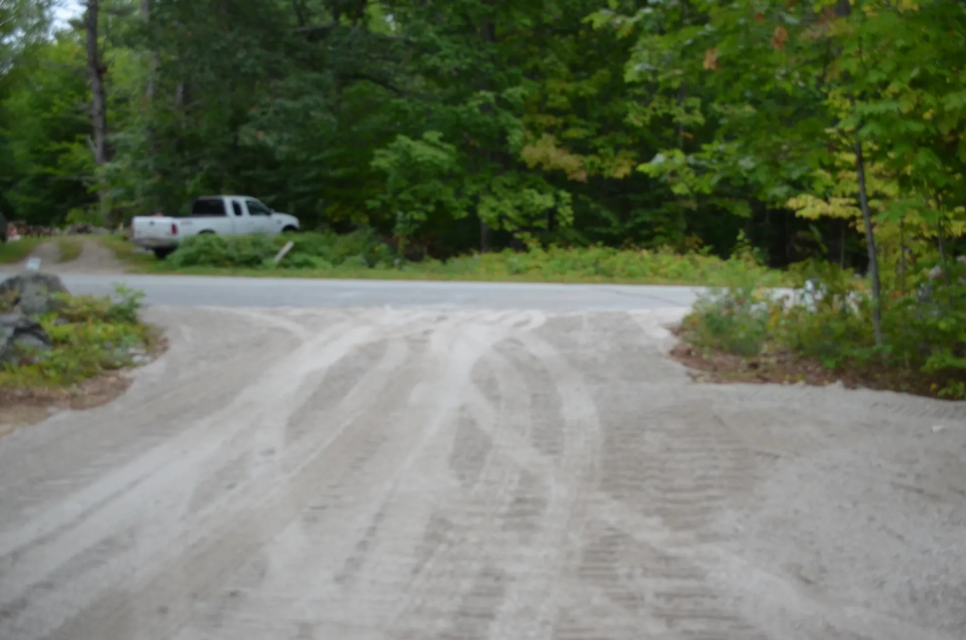A white truck is parked on the side of a dirt road.