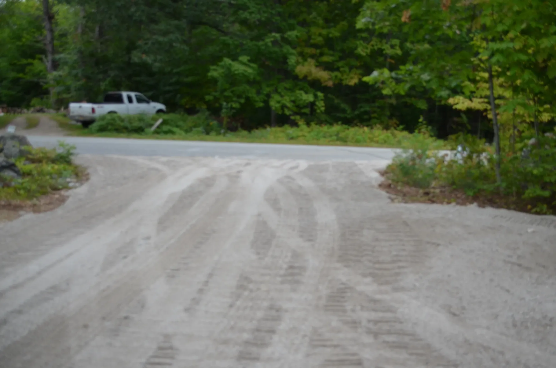 A white truck is parked on the side of a dirt road.