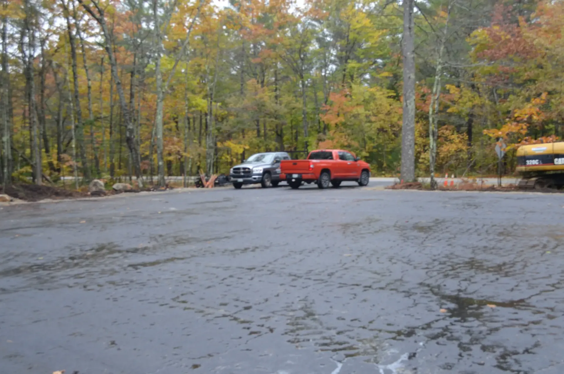 Two red trucks are parked in a parking lot with trees in the background