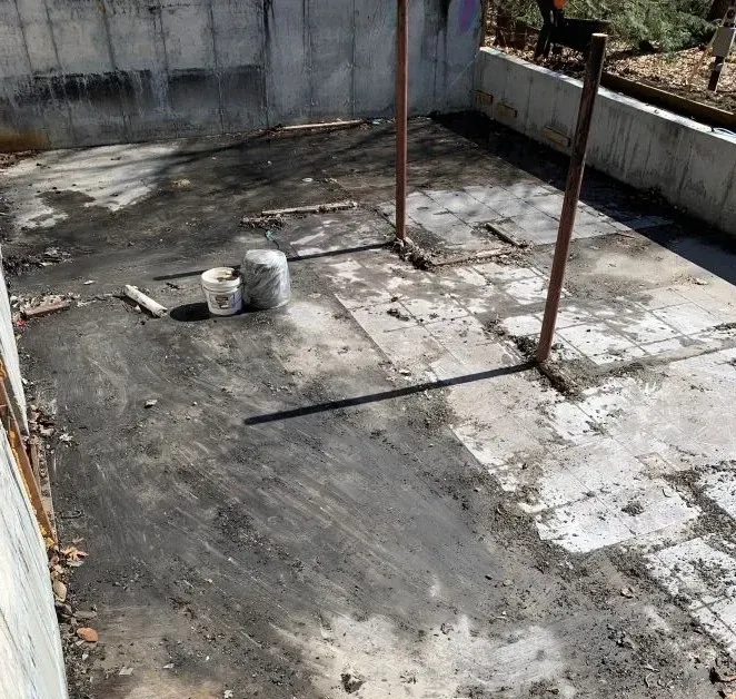 A dirty concrete floor with a bucket of paint on it