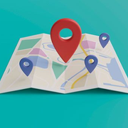 Folded paper map with red and blue location pins on a turquoise background