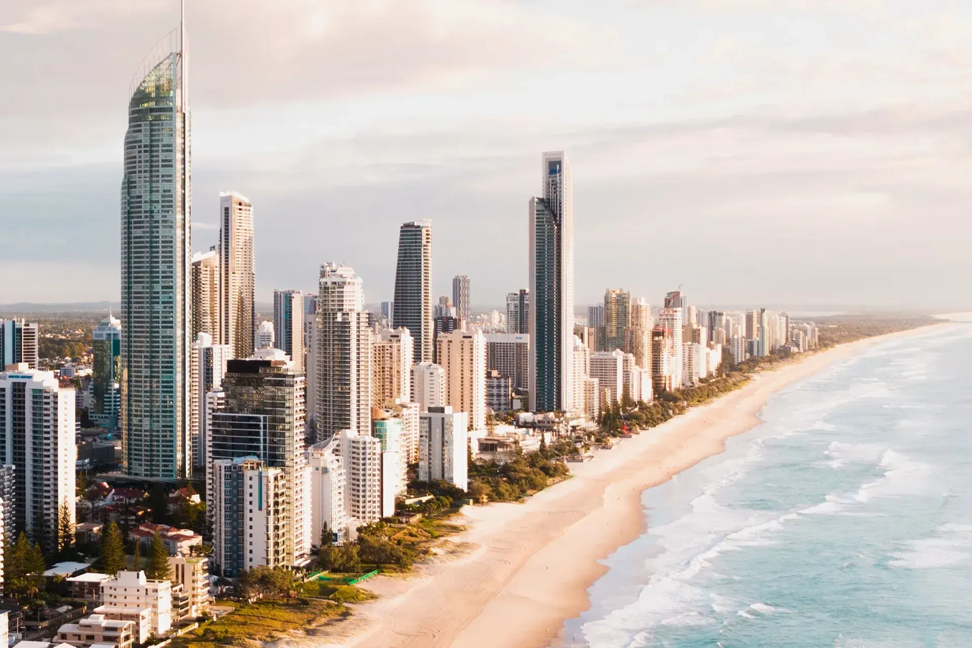 Beachfront skyline with tall modern towers beside a sandy shore and turquoise water
