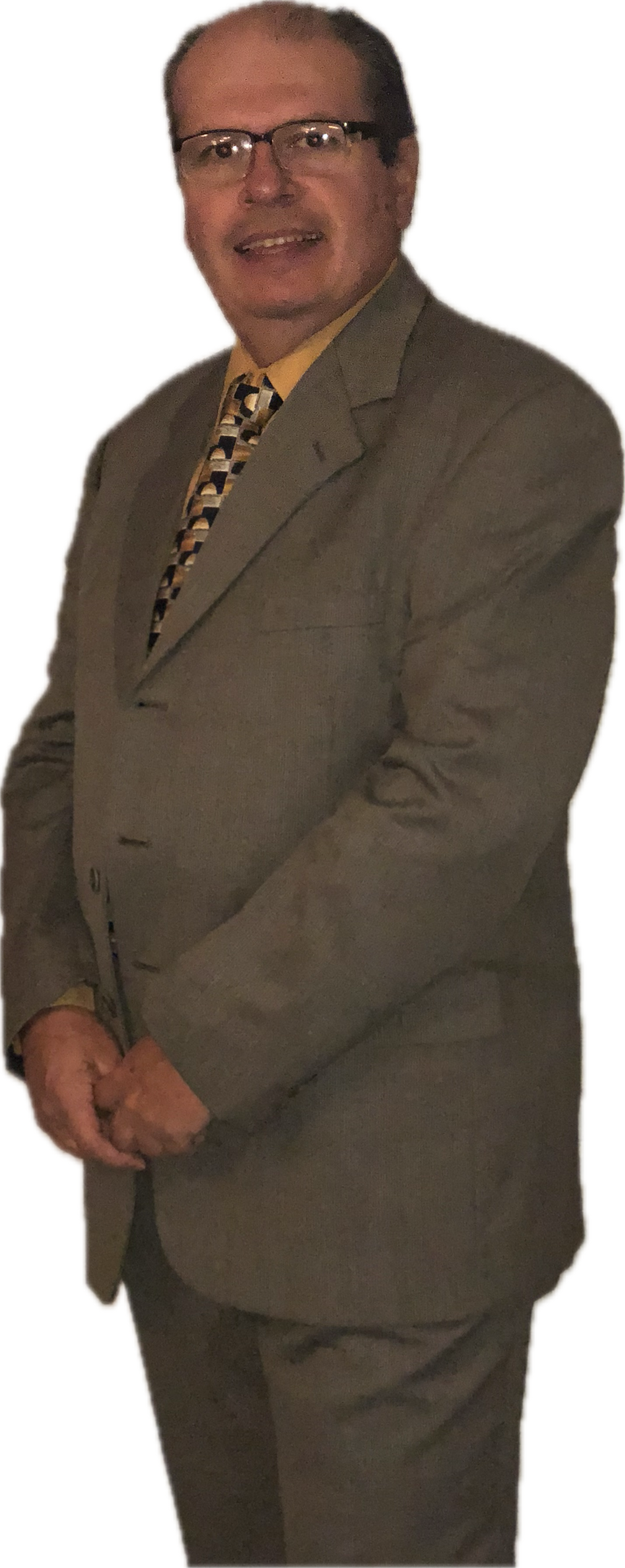 Hombre con traje, gafas, sonriendo levemente, de pie.