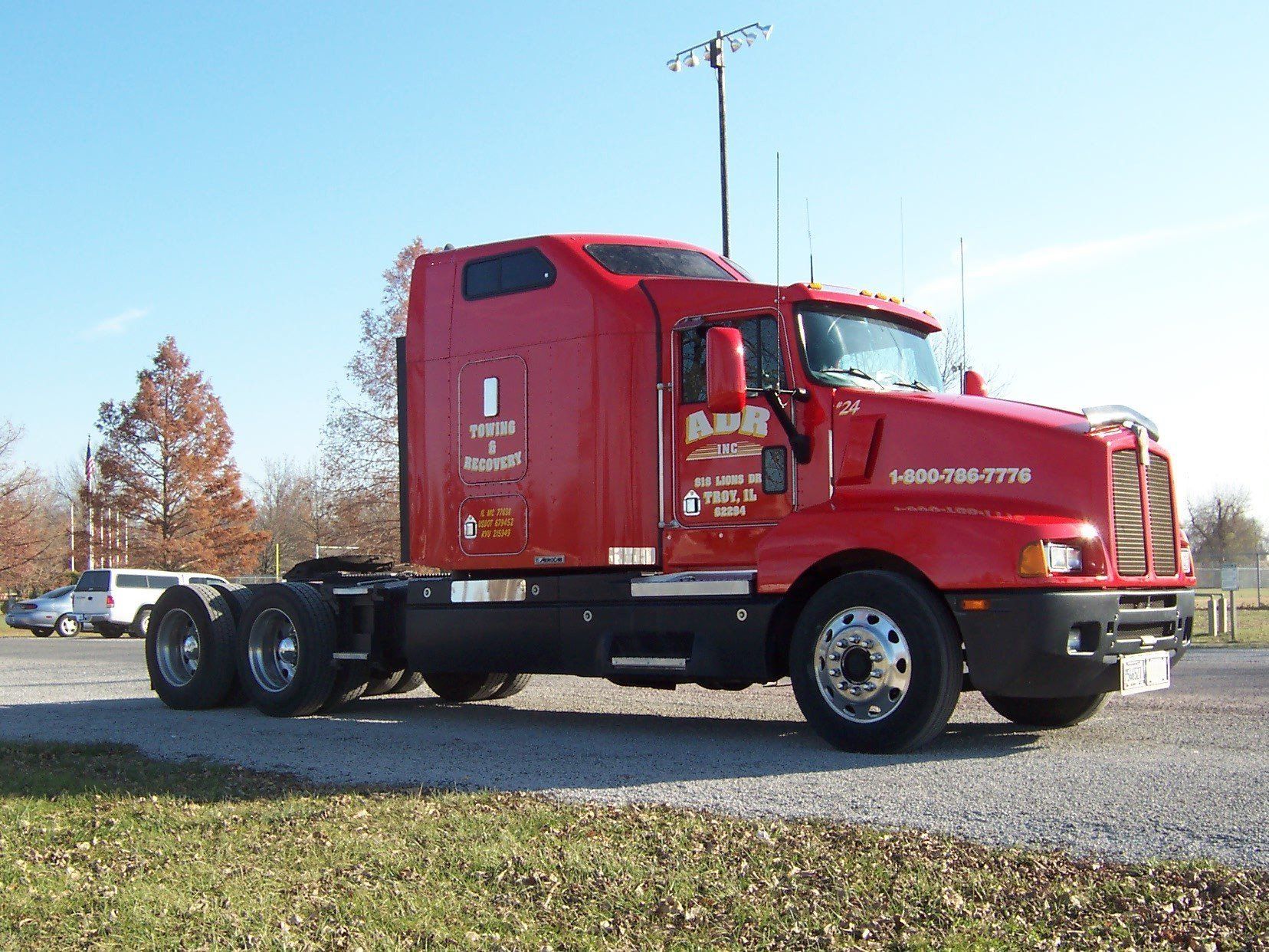 Red semi-truck cab parked on a gravel lot under a clear blue sky