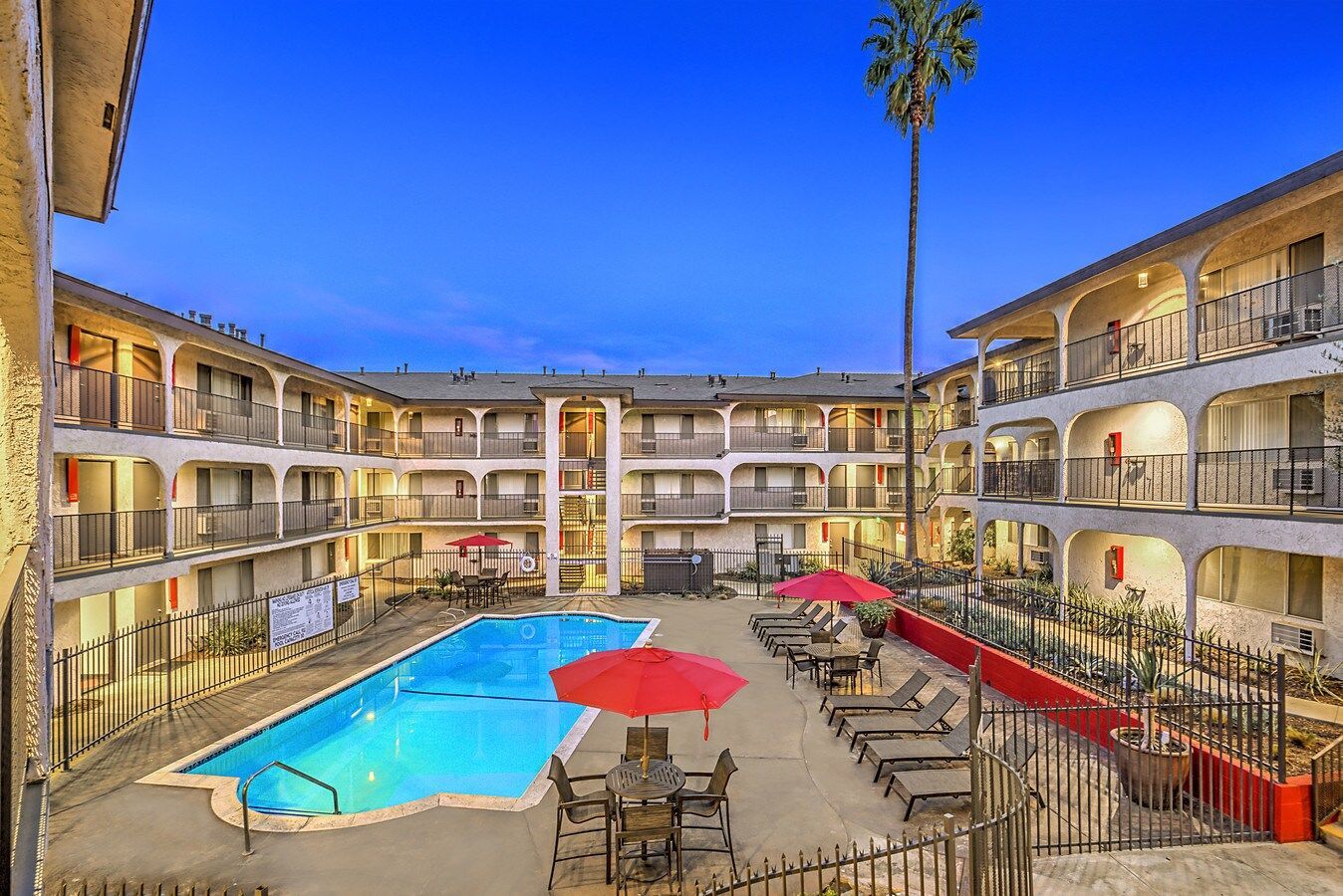 There is a large swimming pool in the middle of a hotel.