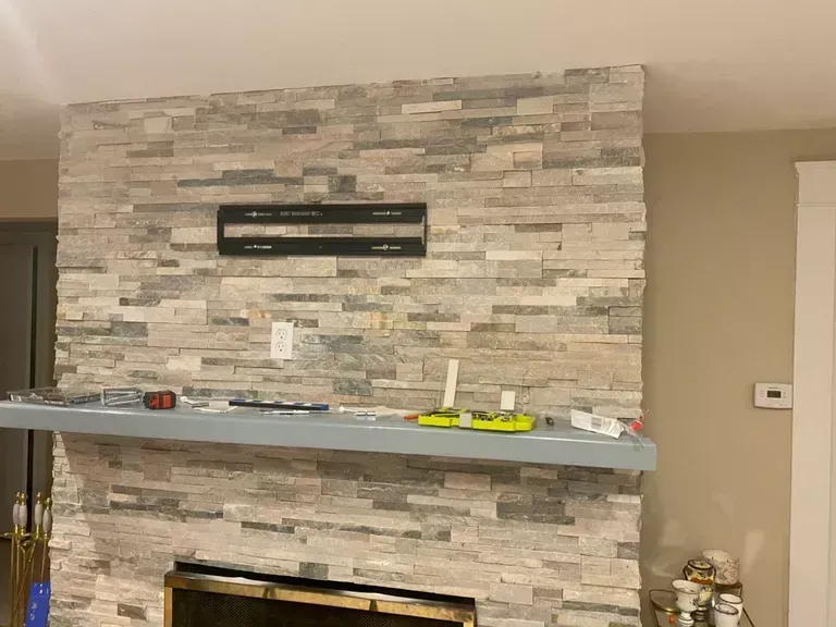 Living room fireplace with stacked stone wall and gray mantel shelf