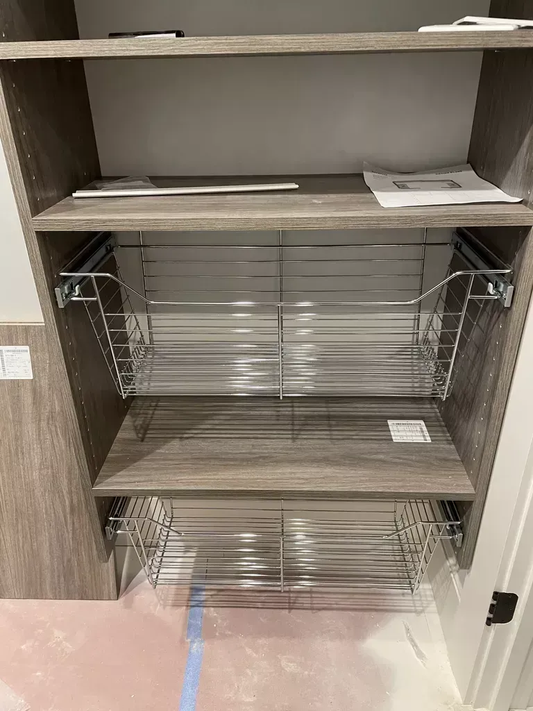 Open cabinet with pull-out wire shelves and wooden shelves inside.