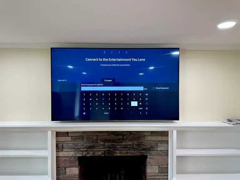 Wall-mounted TV displaying a payment screen above a brick fireplace in a white living room