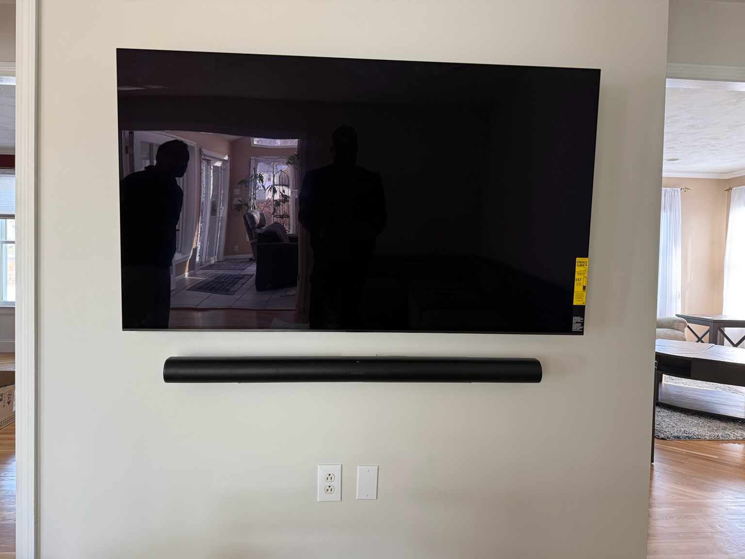 Wall-mounted flat-screen TV above a black soundbar in a bright living room