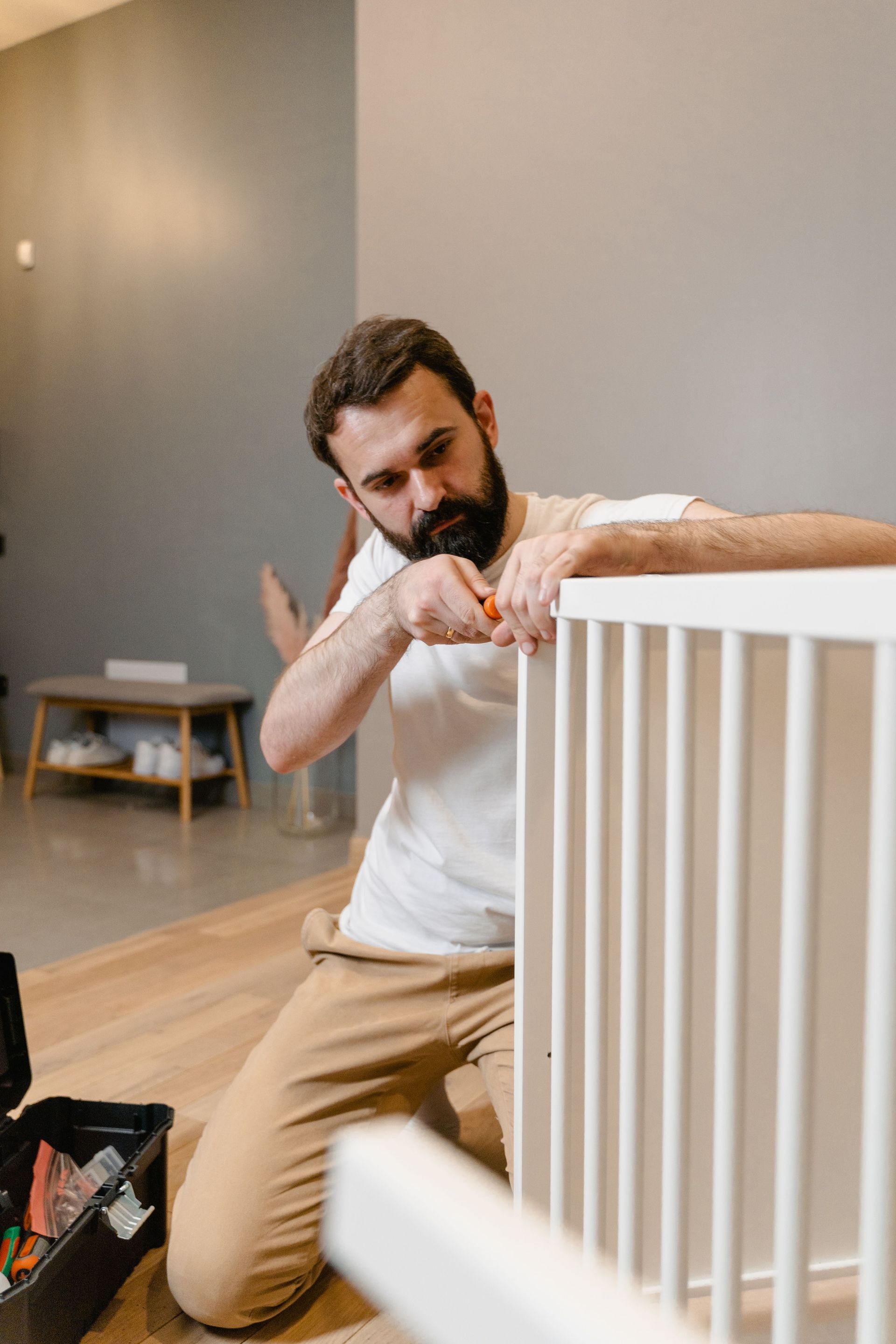 Man kneeling beside a white railing, gesturing with his hands in a modern room.