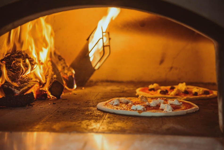 Two pizzas are being cooked in a wood fired oven.