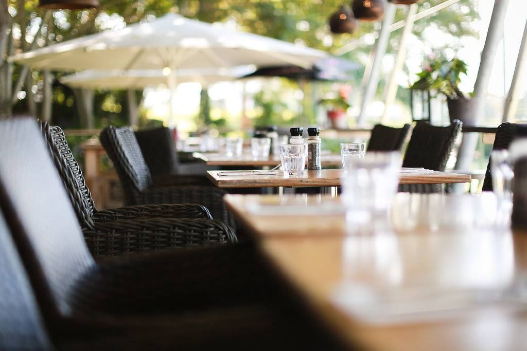 A restaurant with tables and chairs and umbrellas in the background.
