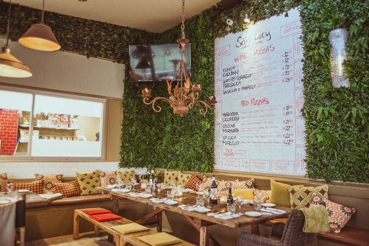 A restaurant with tables and chairs and a menu on the wall.