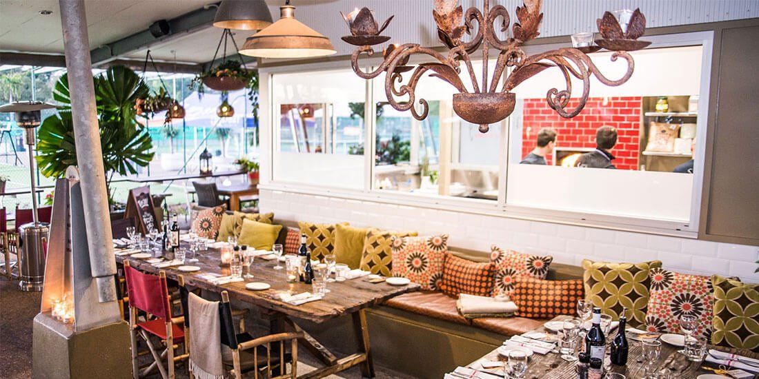 A restaurant with tables and chairs and a chandelier hanging from the ceiling.