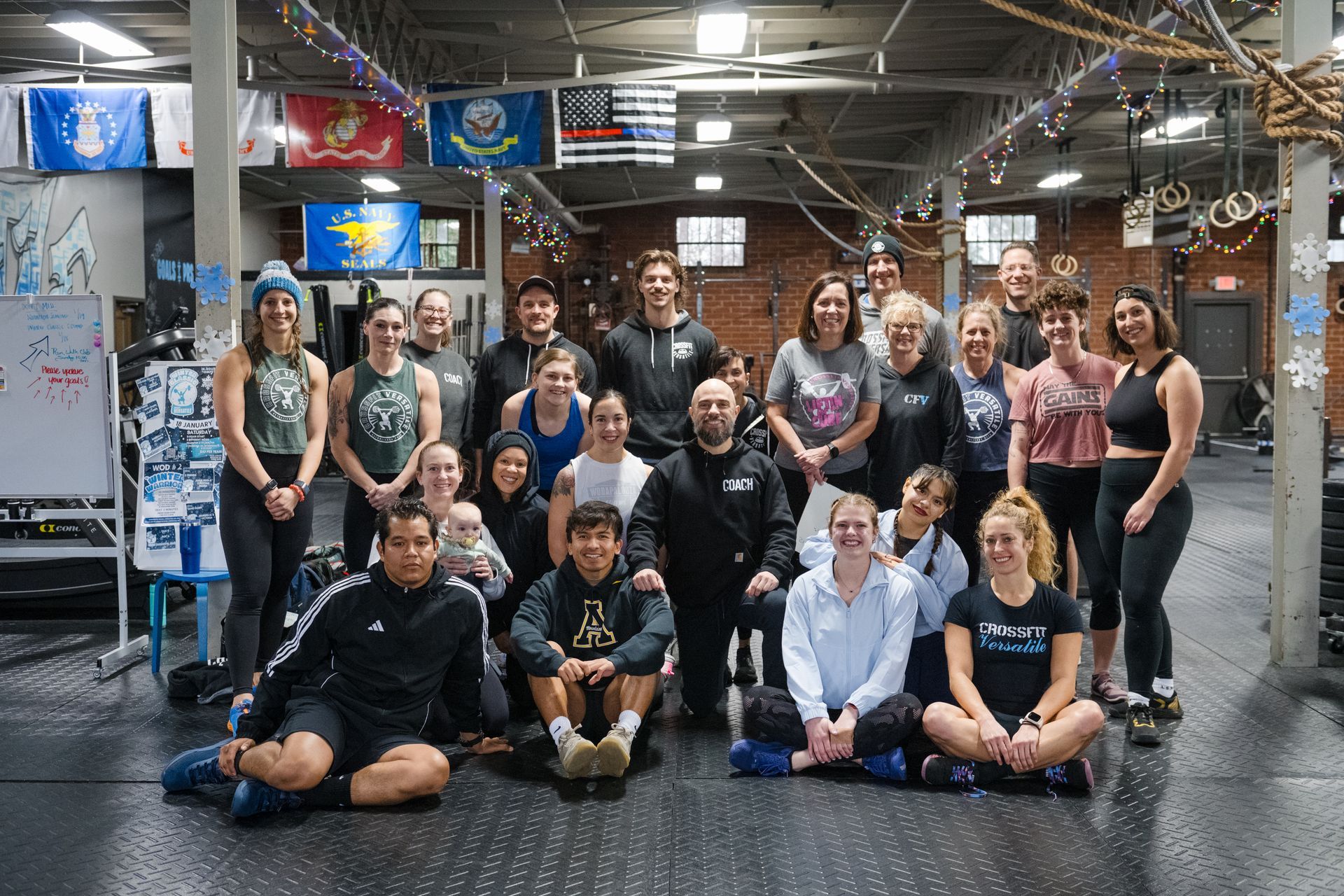A group of gym members are posing for a picture in CrossFit Versatile gym floor.