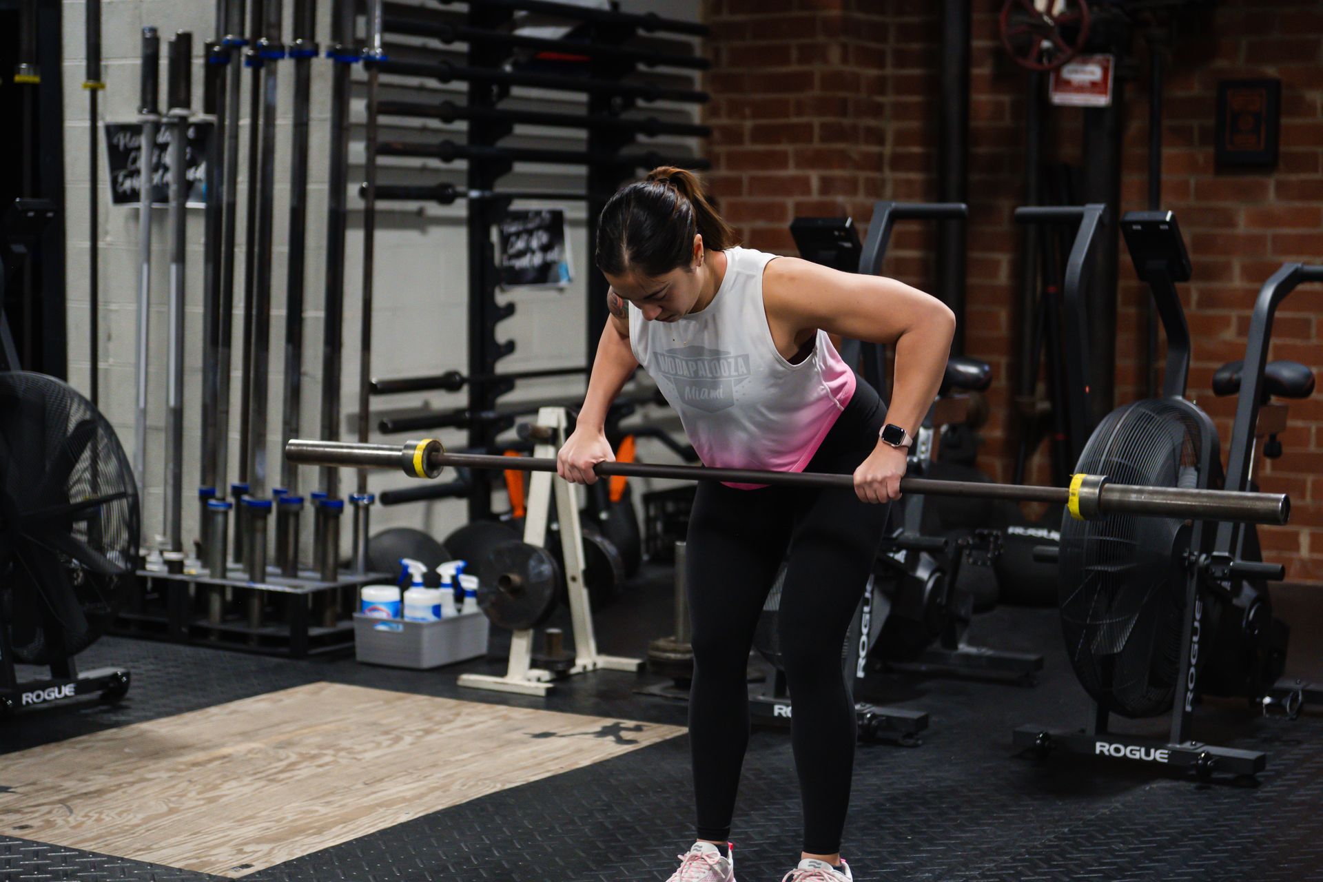 A woman is lifting a barbell in a gym.