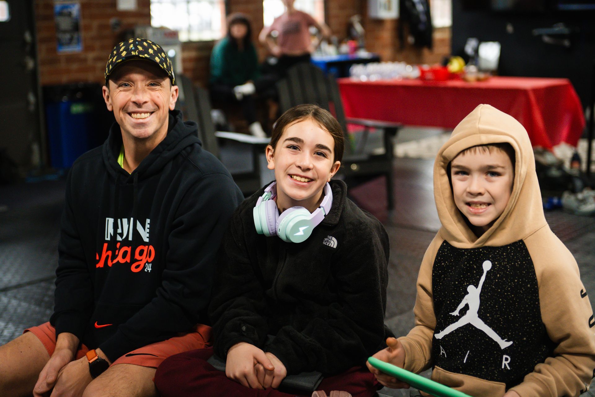 A man and two children are sitting on the floor in CrossFit Versatile.
