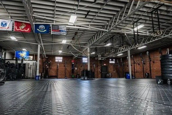 Gym interior with dark tiled floor, equipment, and flags.