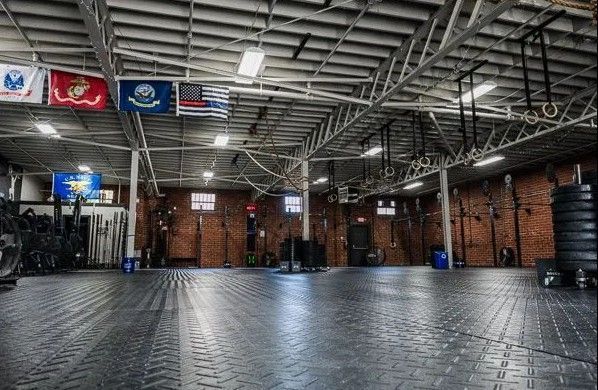 CrossFit Versatile Gym interior with exercise equipment, flags, and a tiled floor.