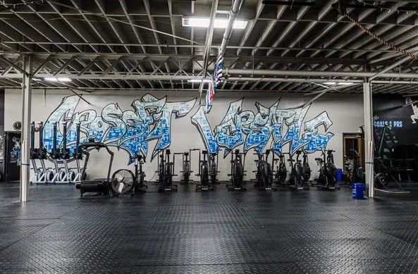Gym interior with exercise bikes and graffiti art on the wall.