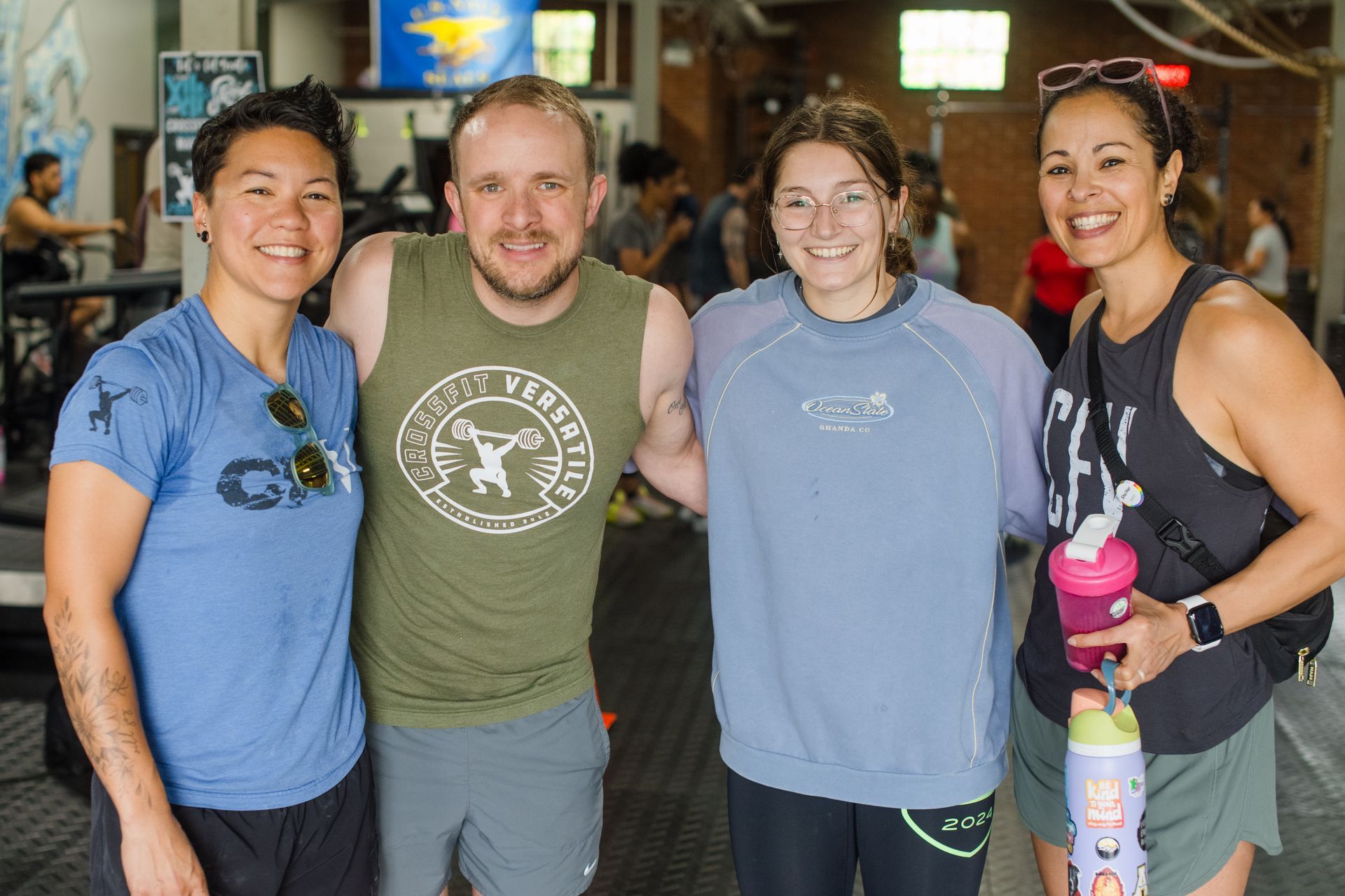 Four people smiling, posing in a gym. Two women on the ends; two people in the middle.