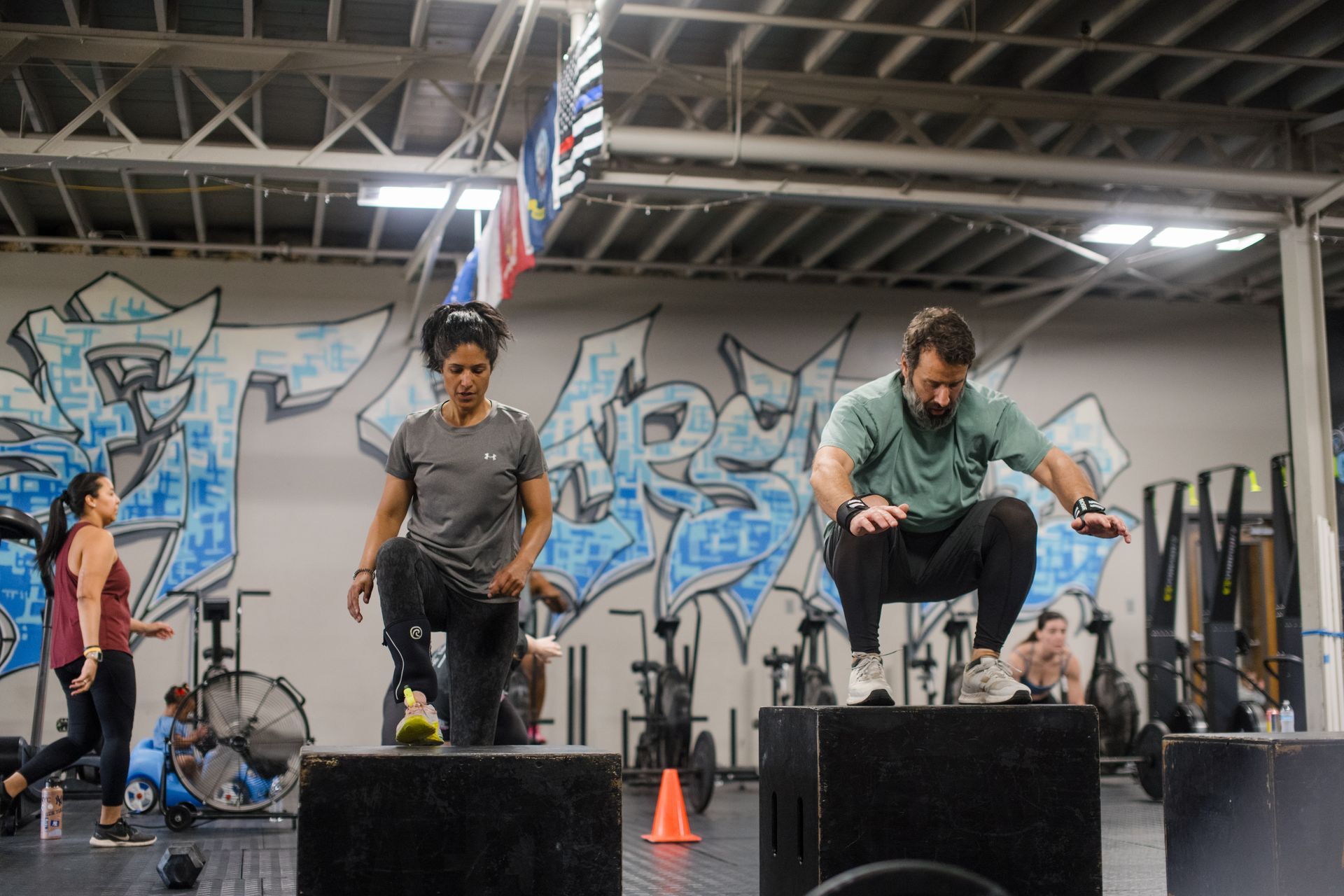 A group of people are squatting on boxes in CrossFit Versatile gym.