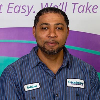 A man in a striped shirt is smiling in front of a sign.