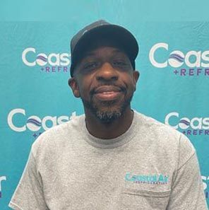 A man in a striped shirt is smiling in front of a sign.