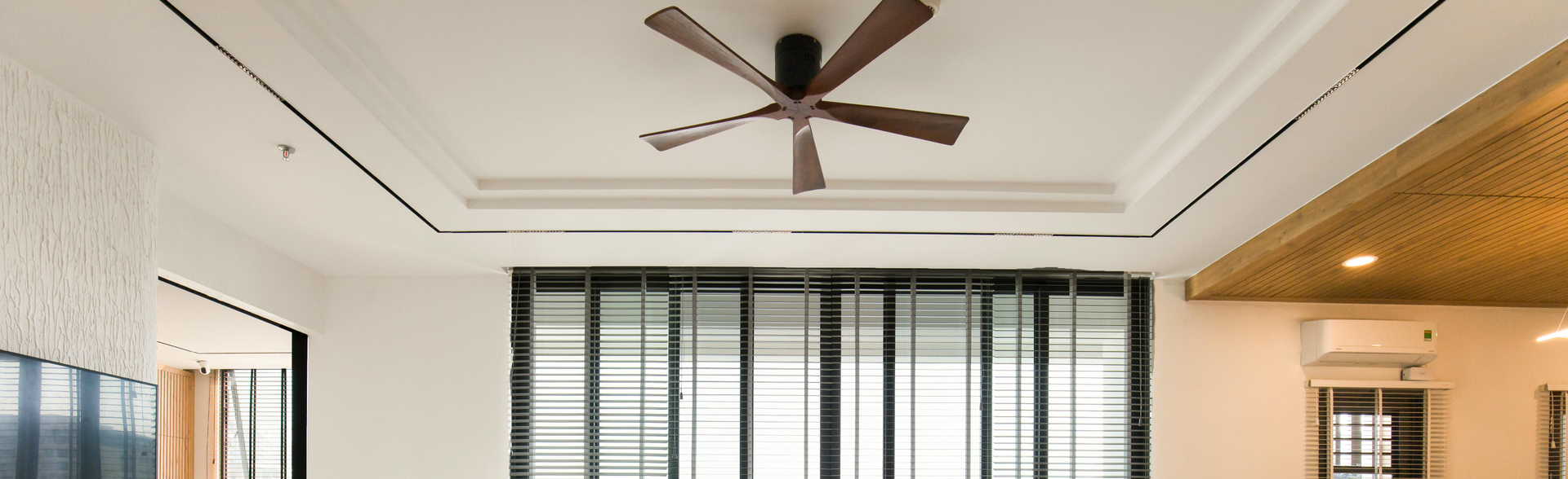 Modern living room with large windows, a ceiling fan, a mini-split, and warm wood accents
