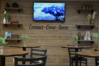 Reception area with rustic wood backdrop, shelves with decor, TV, and table with resources.