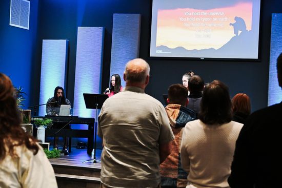 A group of people are sitting in a church with their hands in the air.