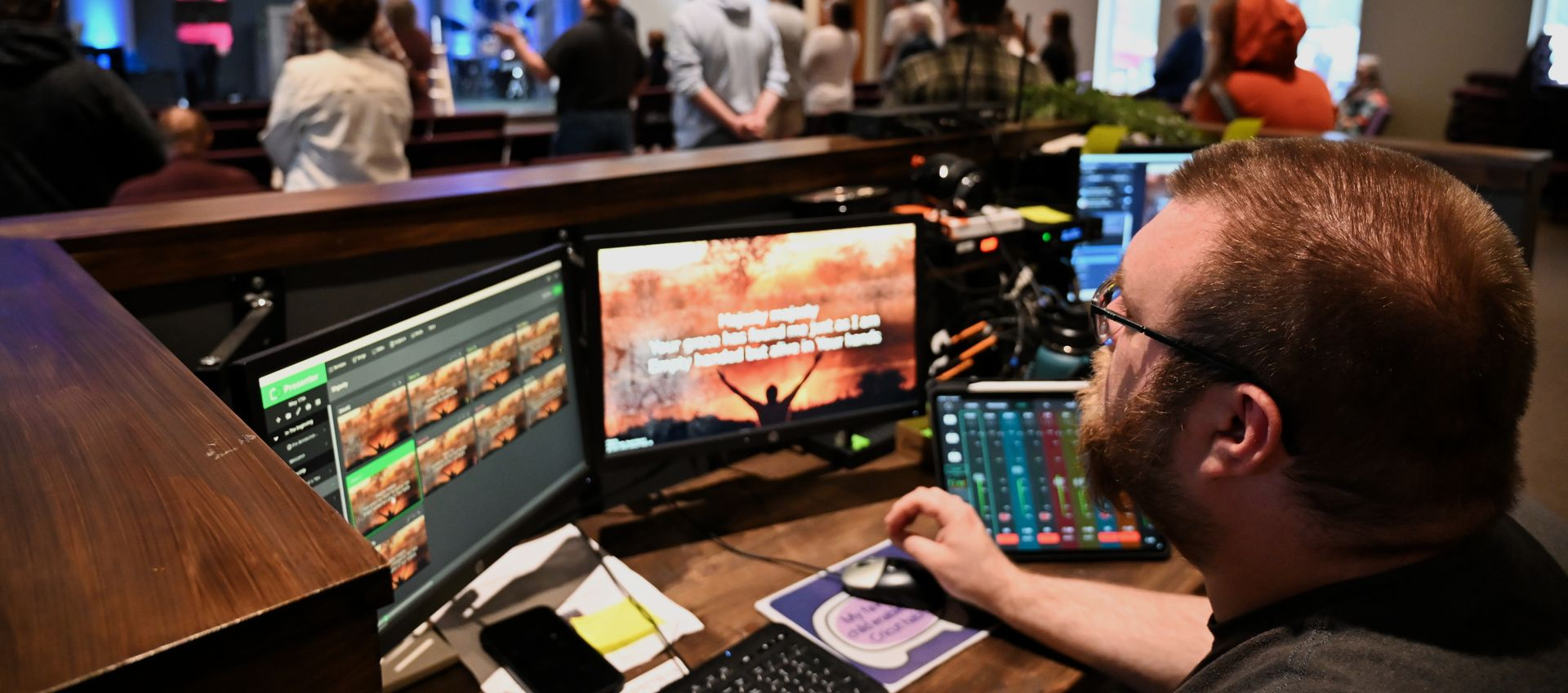 Two men are sitting in front of a computer screen that says ' i am sorry ' on it