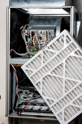 The inside of a furnace with a filter being removed.