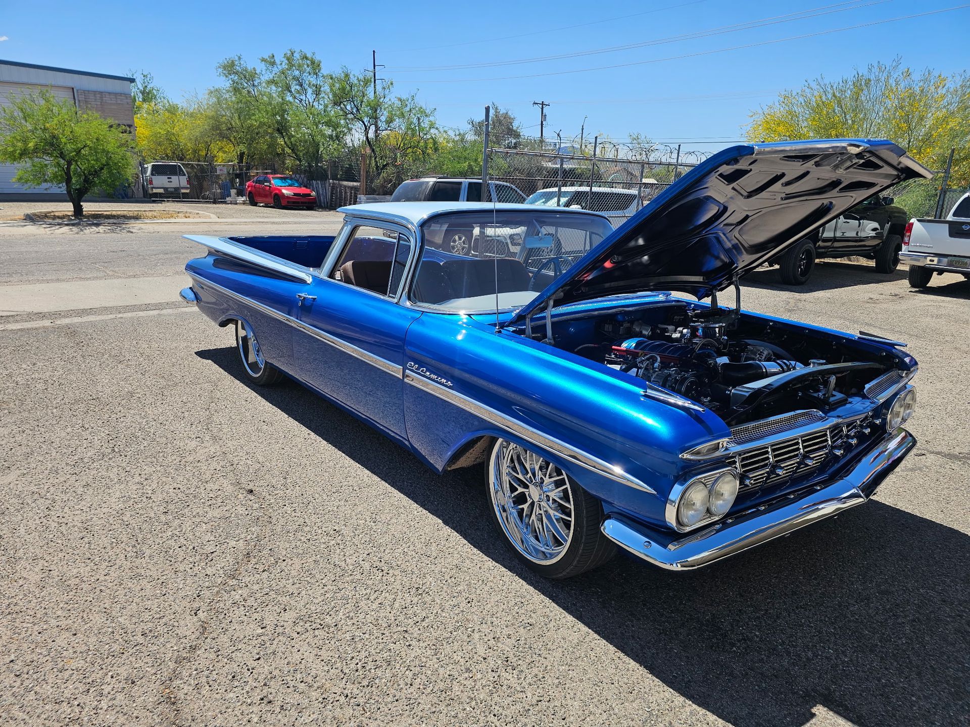 Blue classic car with hood open parked on a sunny lot
