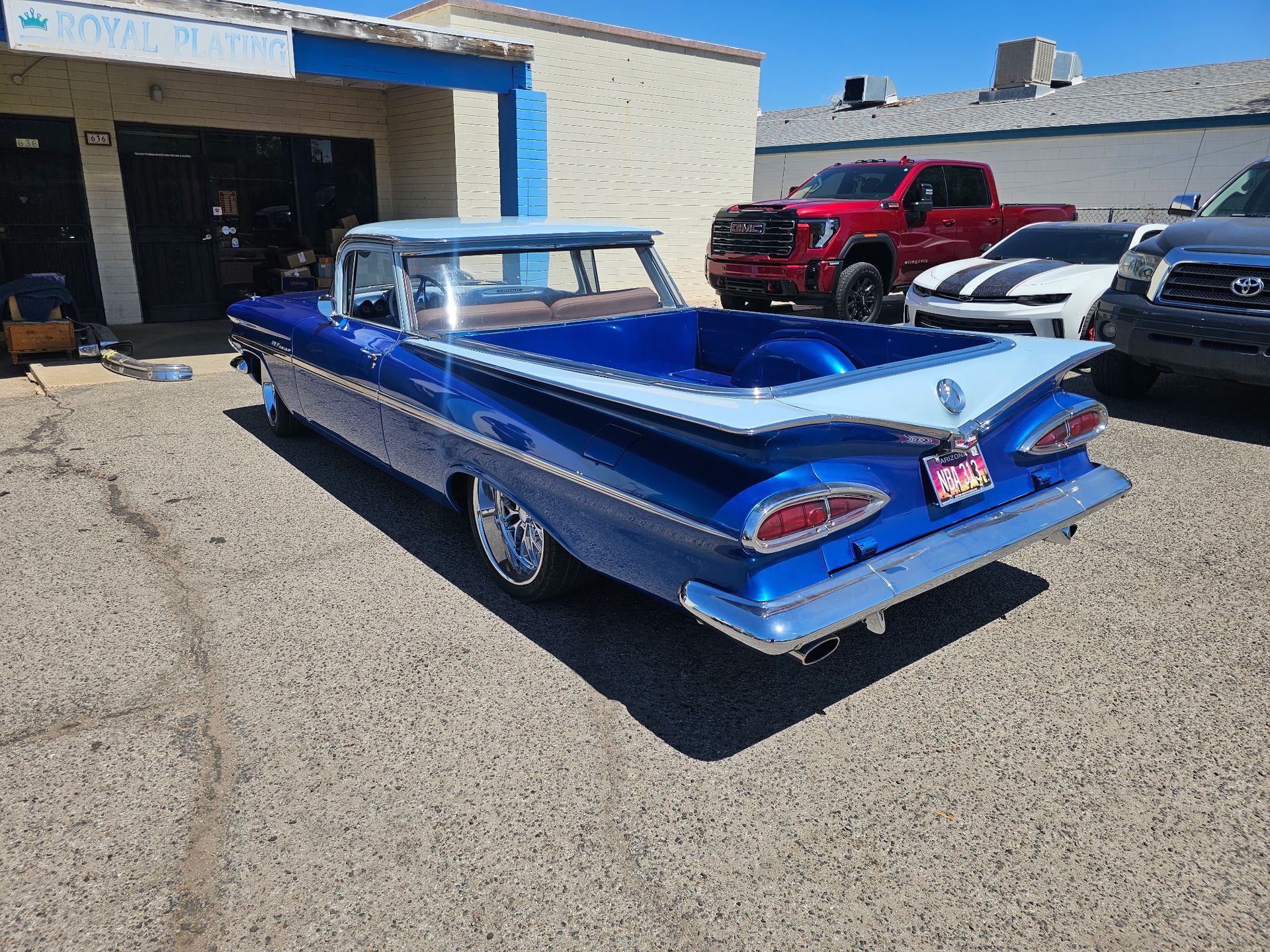 Blue classic convertible lowrider parked outside a garage on a sunny day.