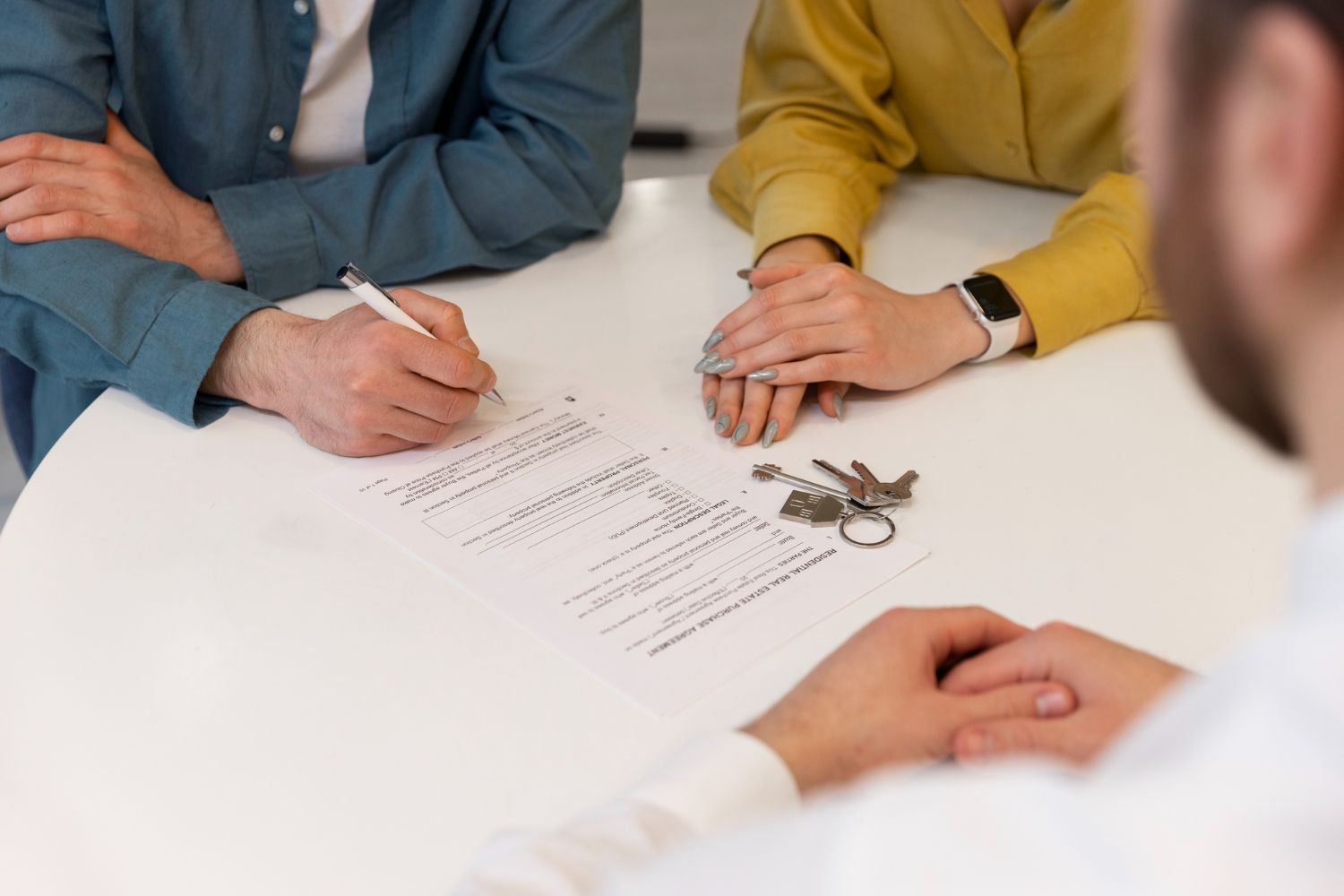 Hands signing a document at a white table during a meeting