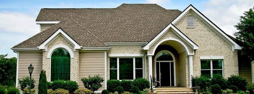 Single-story suburban house with beige siding, white trim, arched entryway, and neatly landscaped front yard