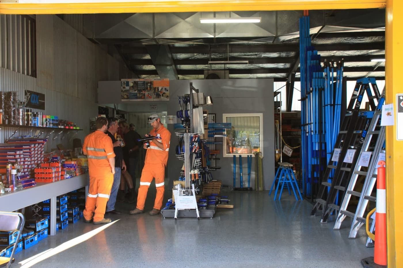 People in Orange Coveralls Inside a Hardware Store — Mount Isa Hire Service & Sales in Mount Isa City, QLD