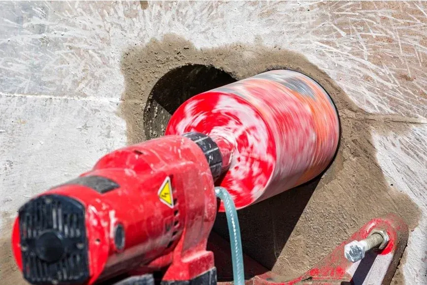 Red power drill with red-and-white paint on a concrete wall surface — Mount Isa Hire Service & Sales in Mount Isa City, QLD