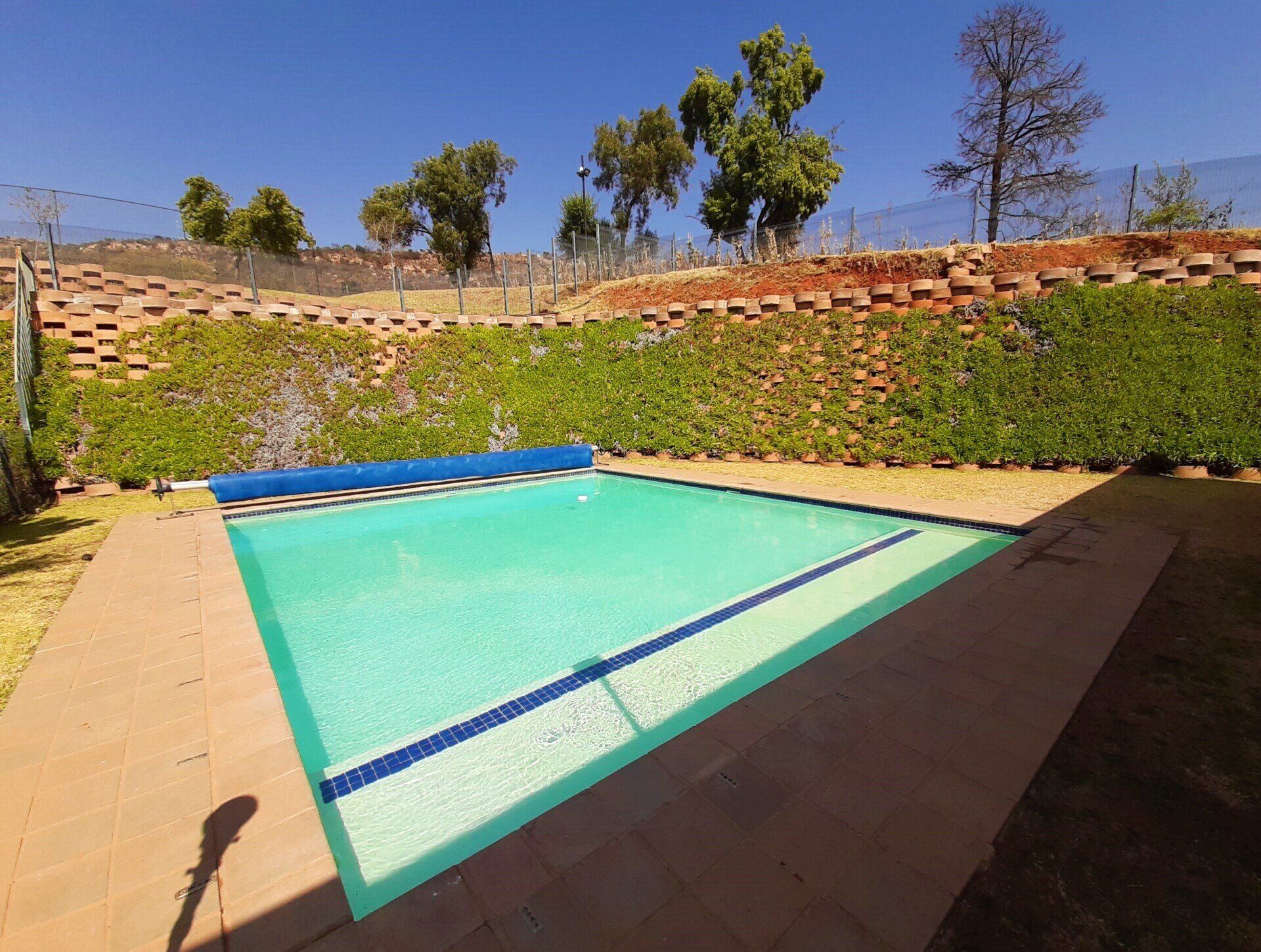 a large swimming pool is surrounded by a fence and trees .