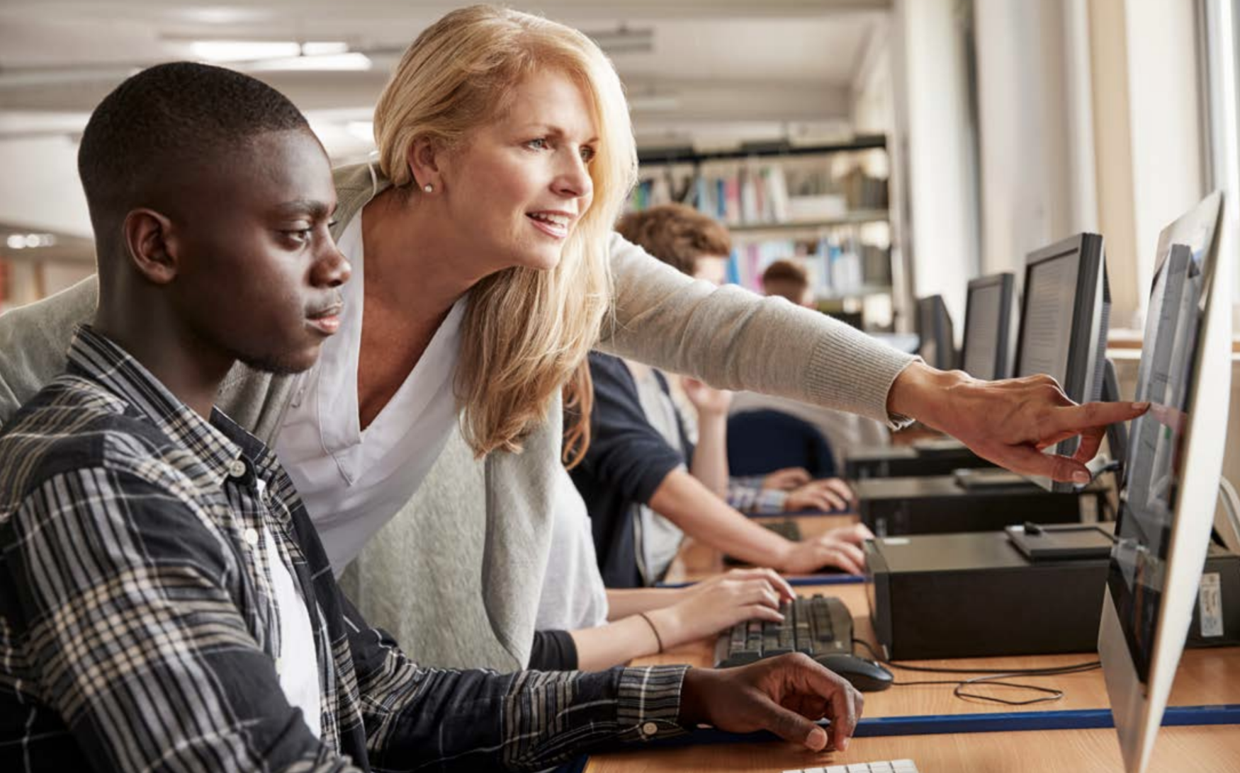A woman is teaching a man how to use a computer.