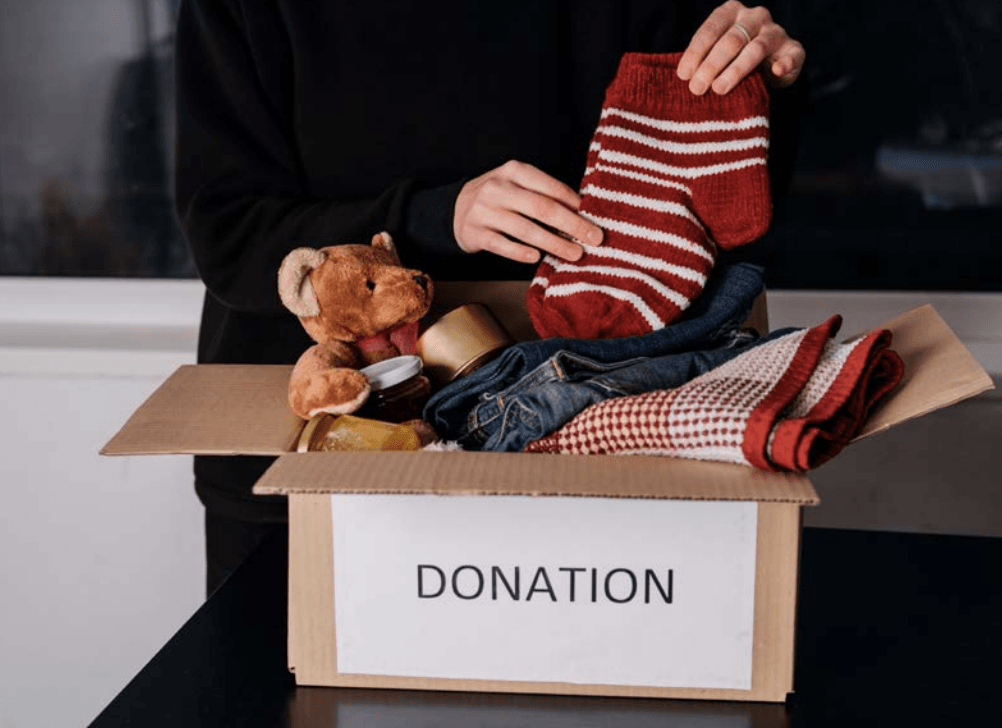 A person is putting a pair of socks in a donation box.