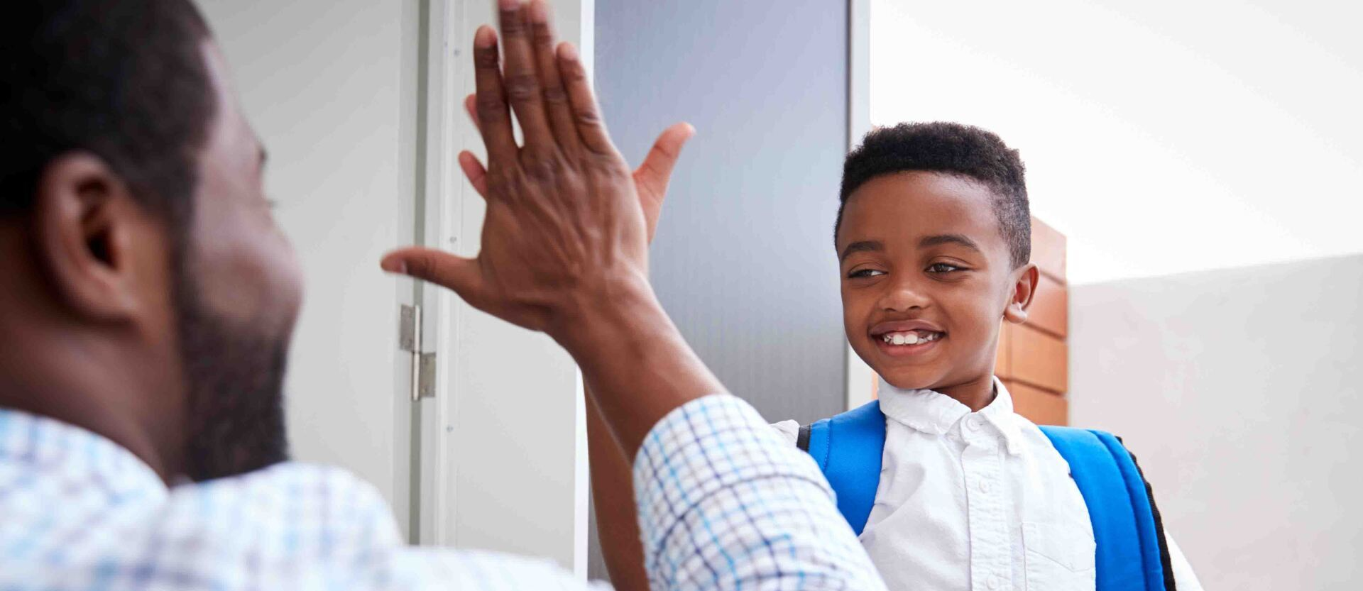 A man and a boy are giving each other a high five.