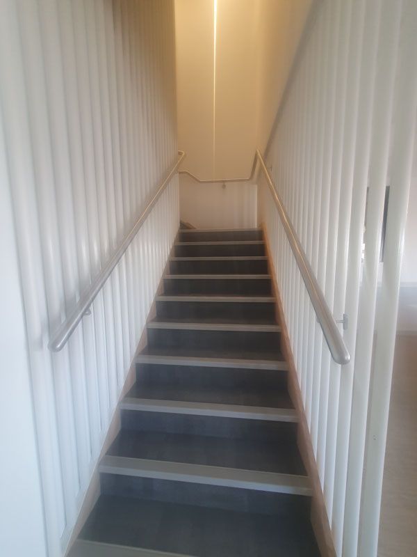 A set of stairs leading up to the second floor of a building with a white railing.