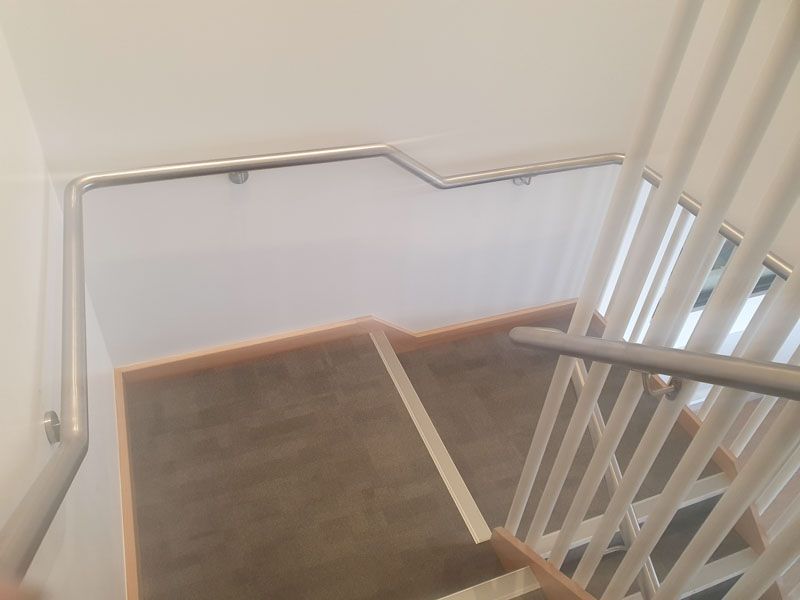 A staircase with a stainless steel railing and a white wall.