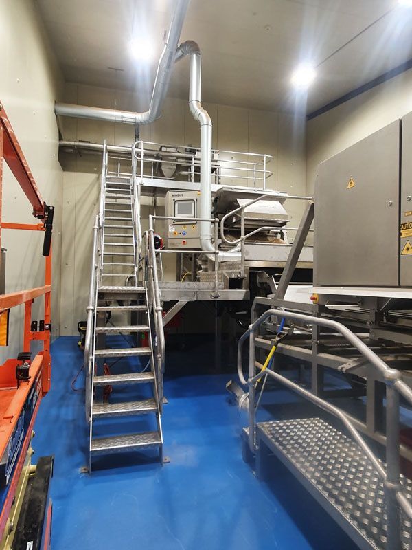 A room with stairs leading up to a machine in a factory.