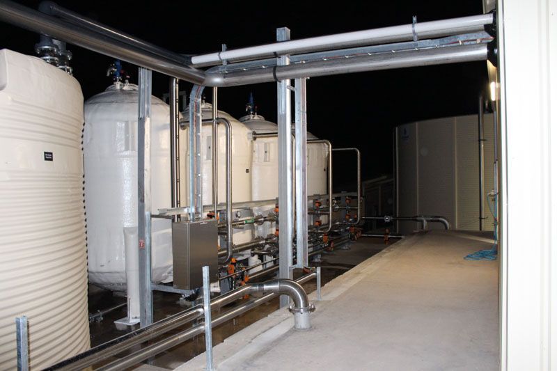 A row of tanks and pipes in a factory at night.